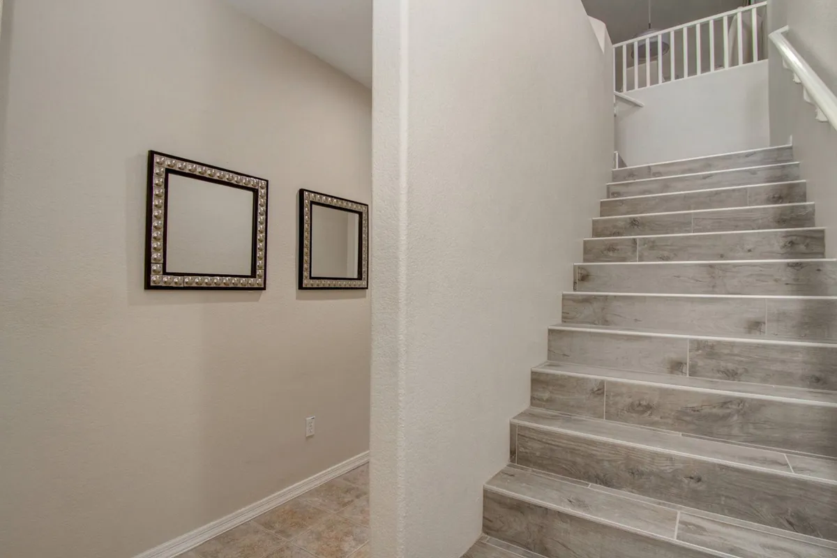 A welcoming entryway featuring a staircase with elegant mirrors along the wall, creating a sense of openness and making a strong first impression. The area is well-lit and inviting, suggesting a safe and comfortable transition from outdoors to indoors.