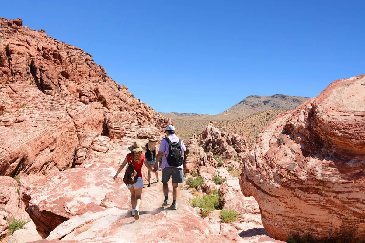 An energetic outdoor scene featuring hikers traversing dramatic rock formations with mountain vistas in the distance. The image captures the spirit of adventure, exploration, and scenic discovery that Scottsdale is known for.