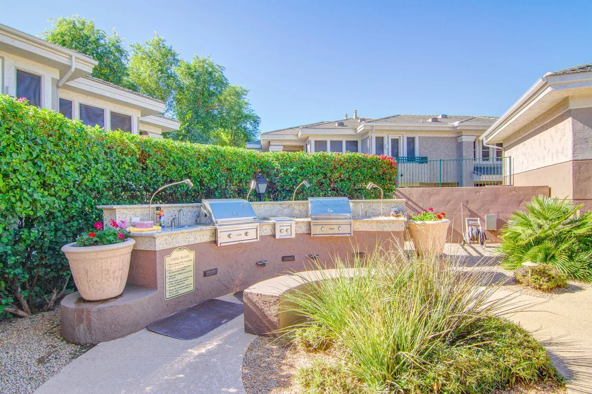 A dedicated barbecue area with a stainless steel grilling station set amidst lush greenery and decorative planters. The area is ideal for group gatherings and outdoor dining, with a relaxed and welcoming atmosphere.