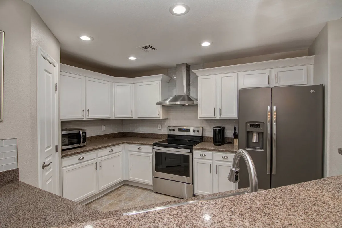A modern kitchen space featuring stainless steel appliances, granite countertops, and crisp white cabinetry. The layout is practical for preparing meals and entertaining, linking visually to the adjacent living areas.
